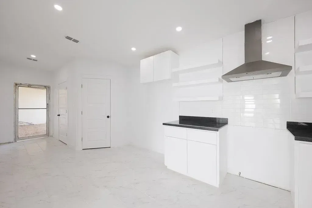 a newly remodeled kitchen with white cabinets and a stainless steel hood