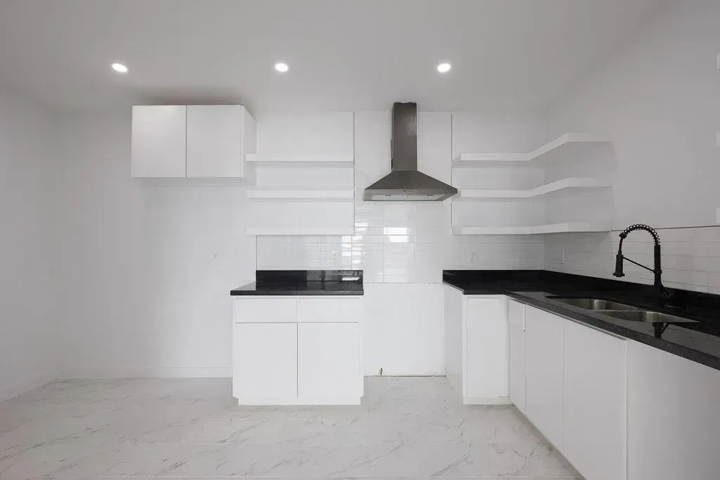 a newly remodeled kitchen with white cabinets and black counter tops