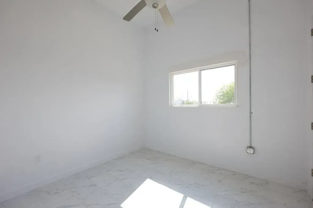 a newly painted room with a ceiling fan and a window