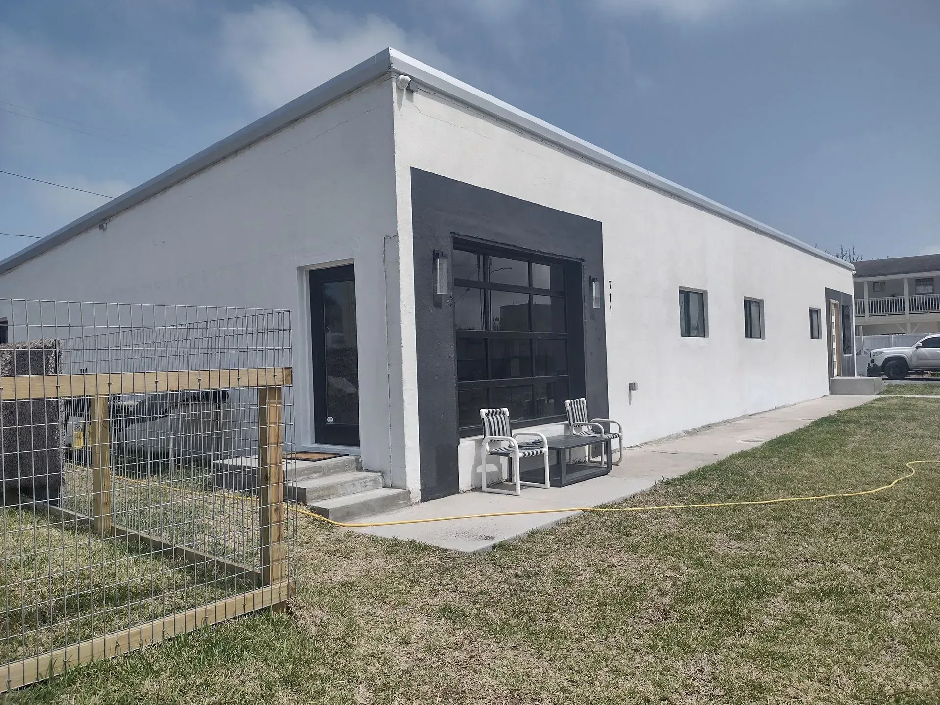 a white house with a fence around it and a table and chairs in front of it