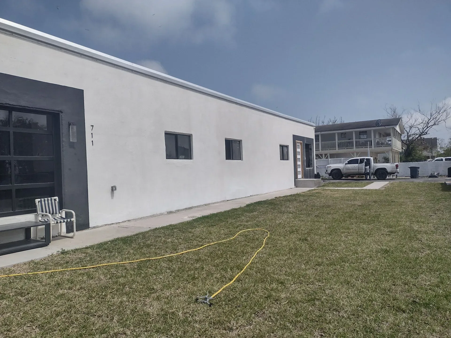 a large white building with a lot of windows is sitting on top of a lush green field