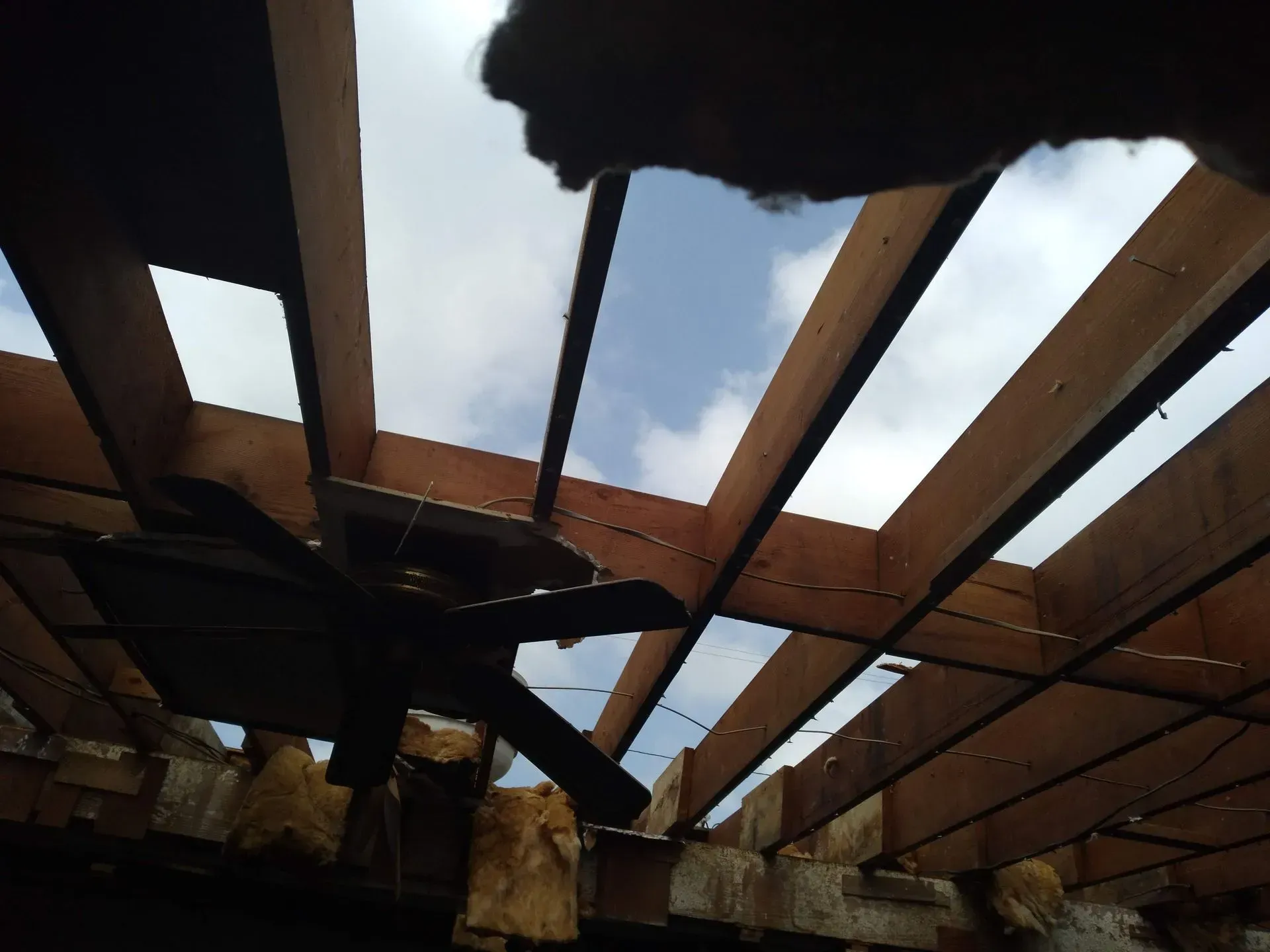 looking up at a ceiling fan in a wooden structure