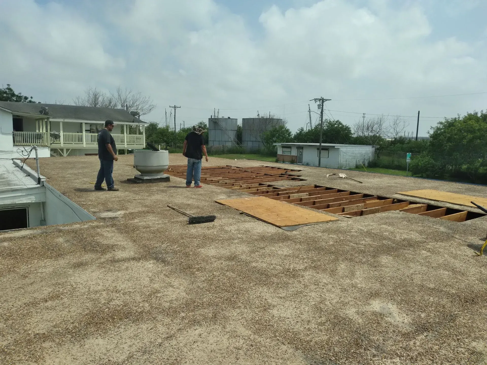 two men are standing in a dirt field in front of a house