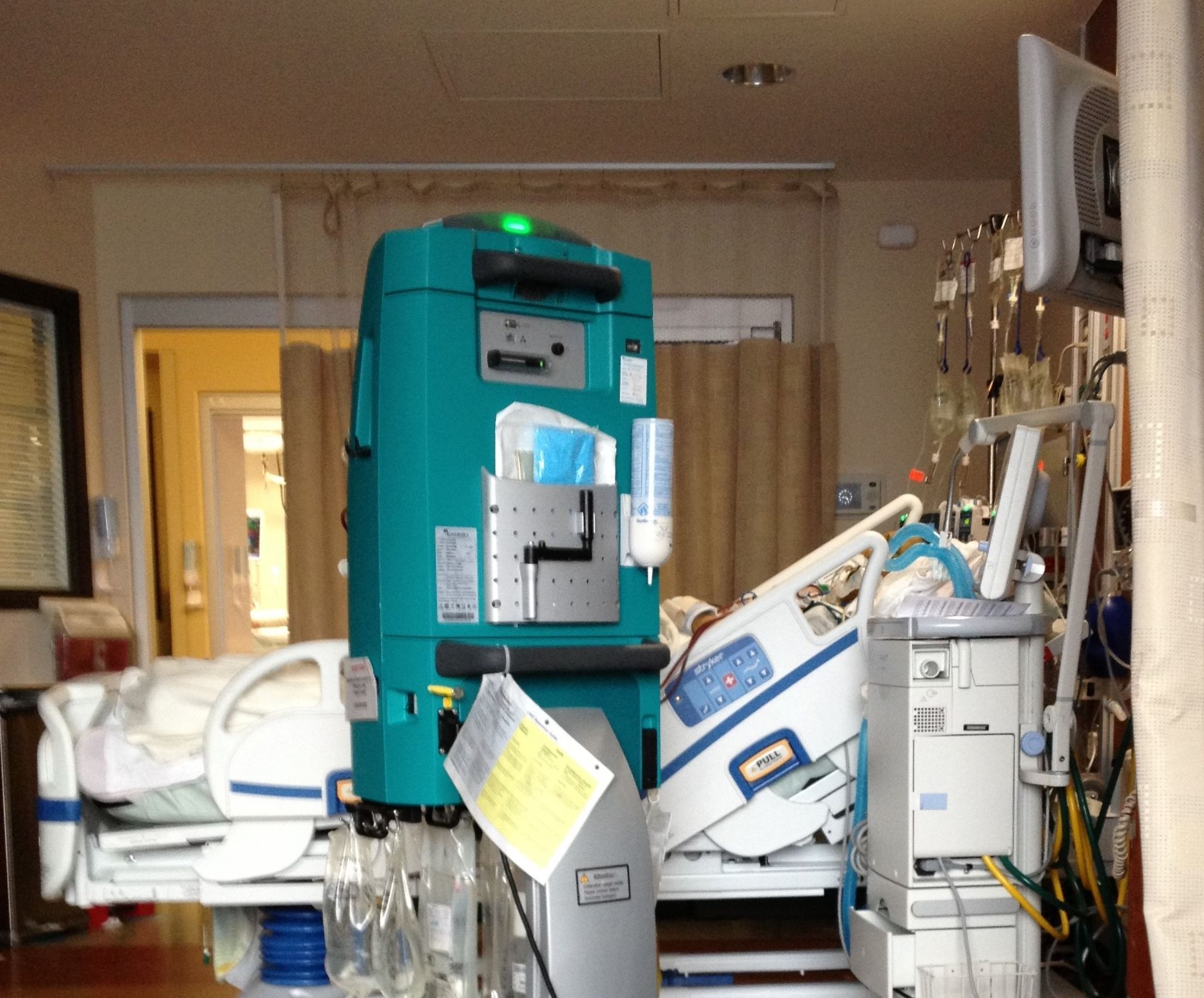 A hospital room with a bed and a green machine