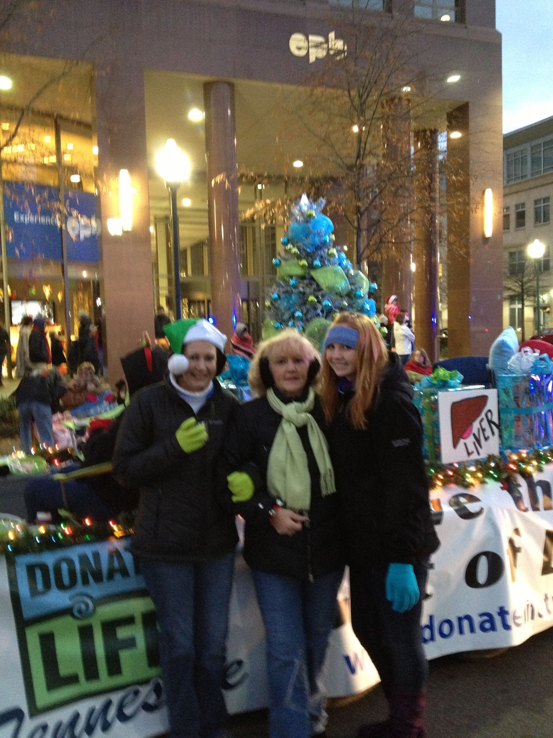 Three people standing in front of a sign that says 