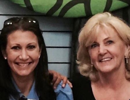 Two women are posing for a picture and smiling for the camera.