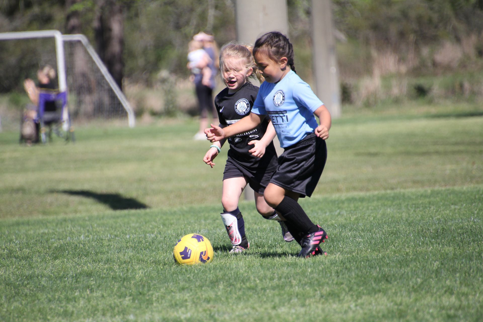 Two young girls playing recreational soccer for Mandeville Soccer Club