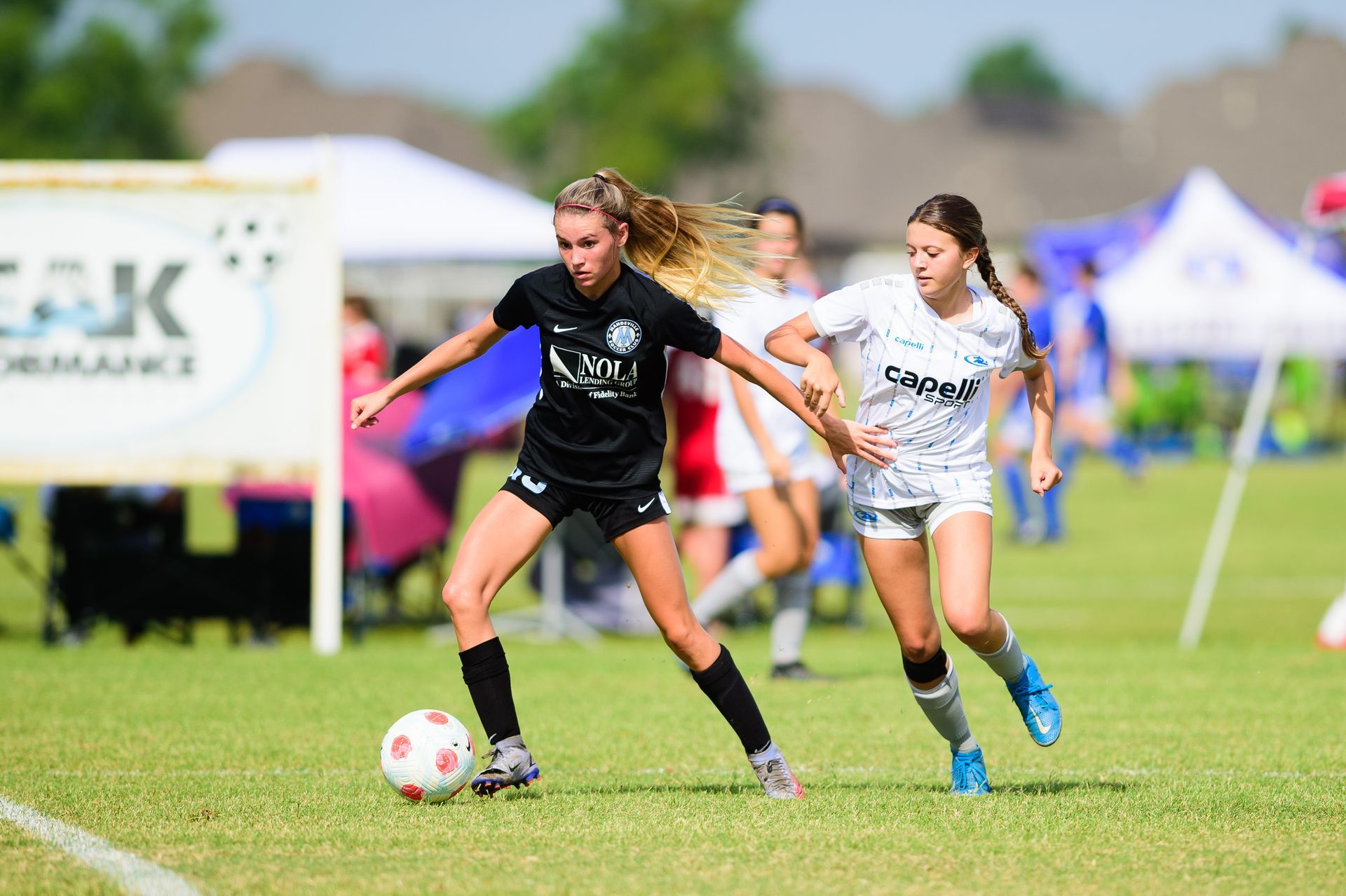 Two young female soccer players in a game for Mandeville Soccer Club