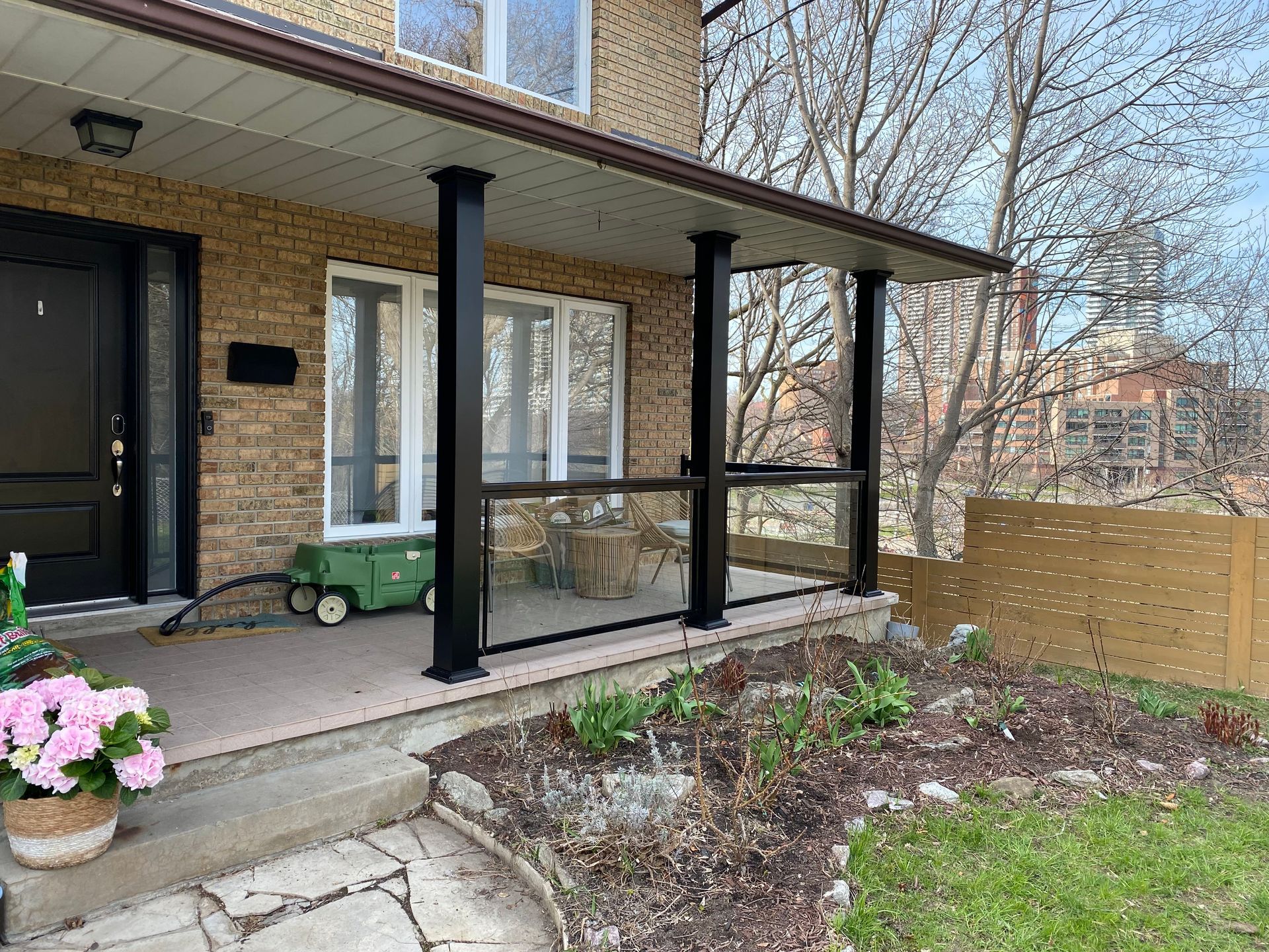 A custom-made frameless glass railing is visible on a porch of a house.