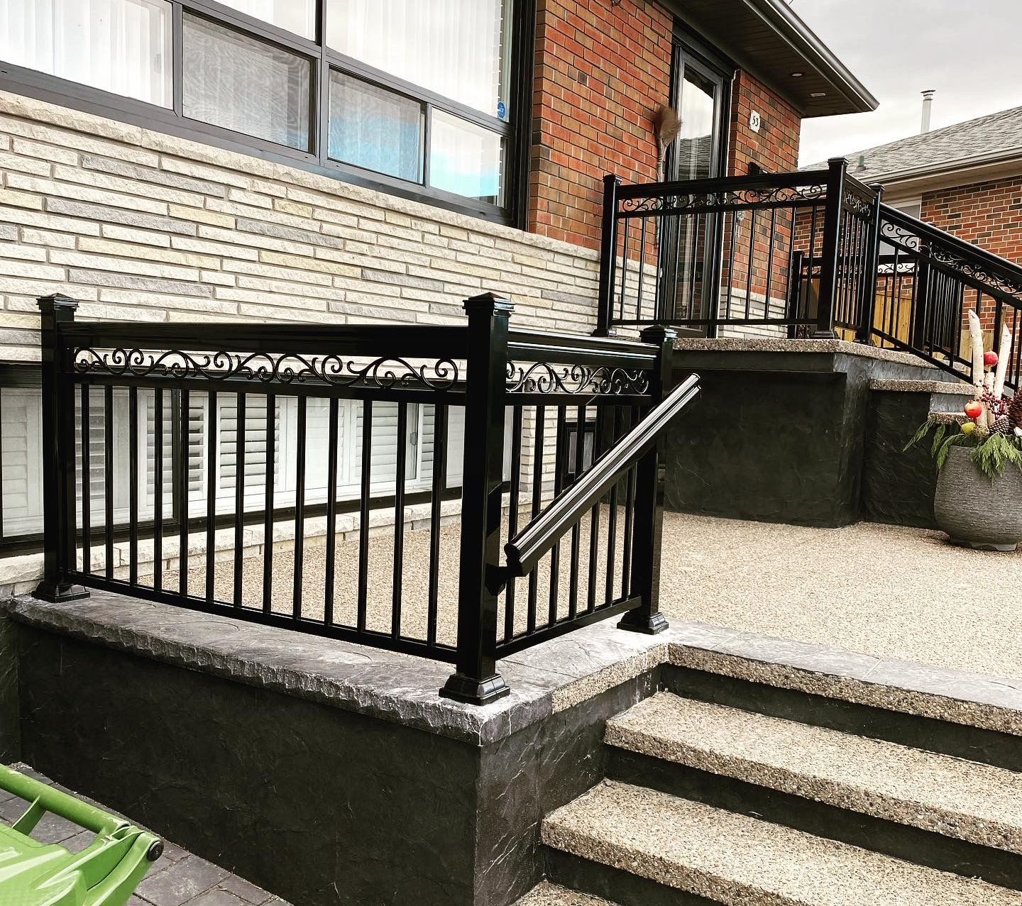 A brick house with a black railing and stairs leading up to it.