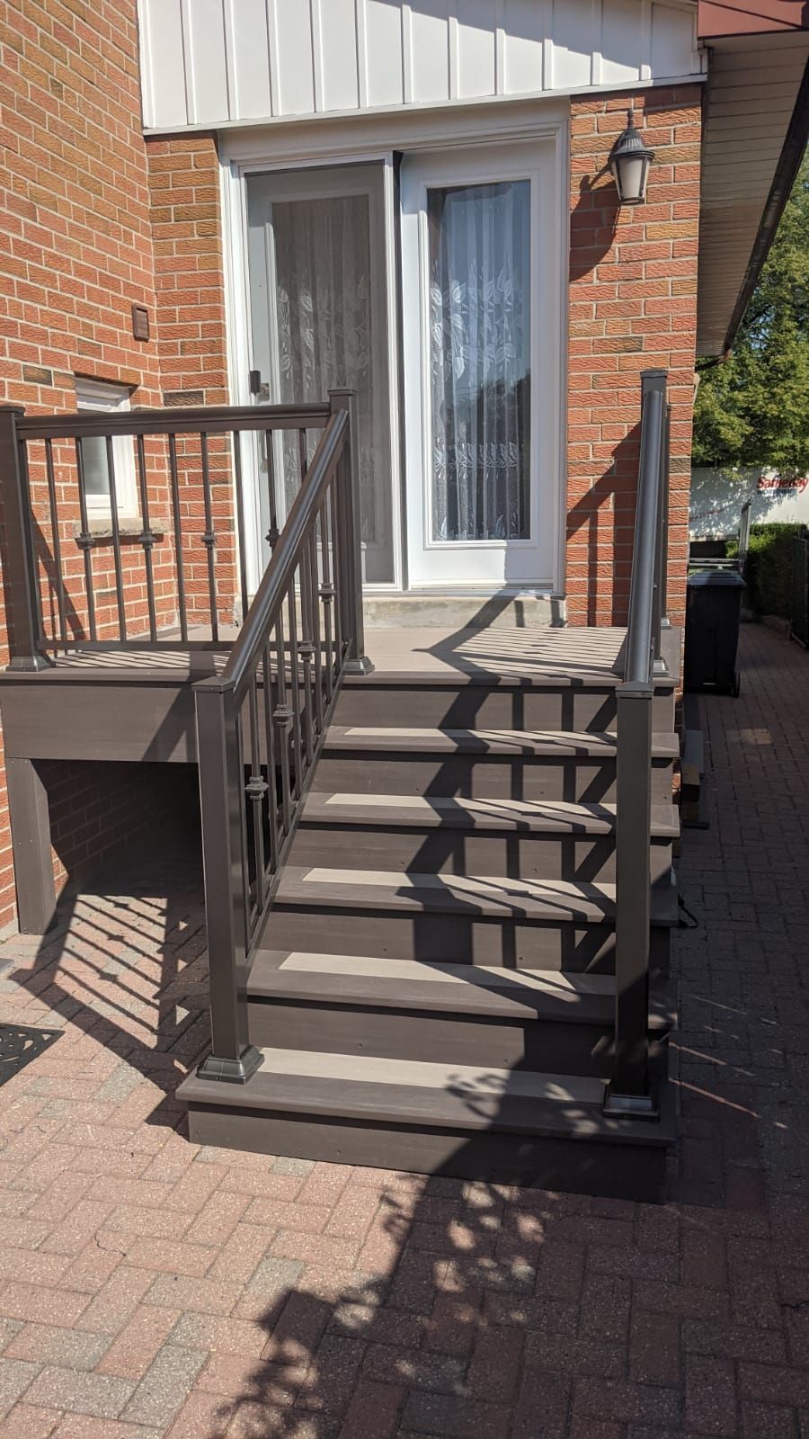 A wooden deck with stairs leading up to a brick house.