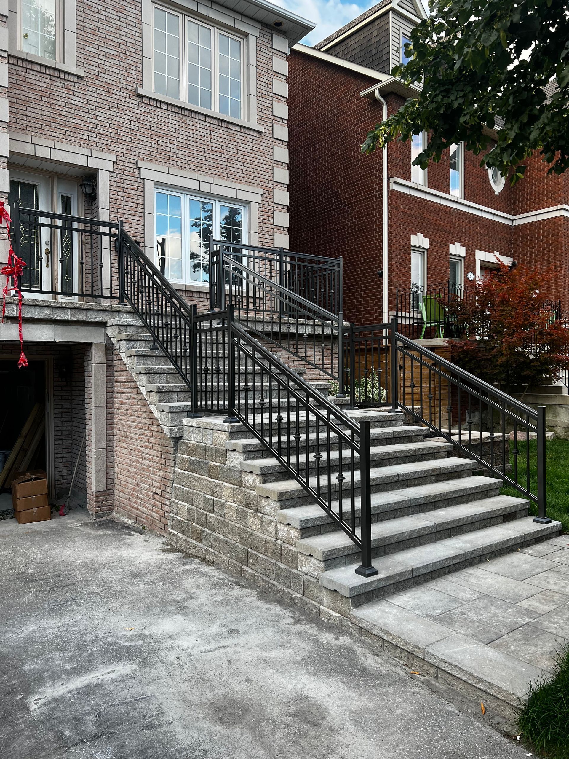 Brick house with black metal railings on outdoor concrete stairs.