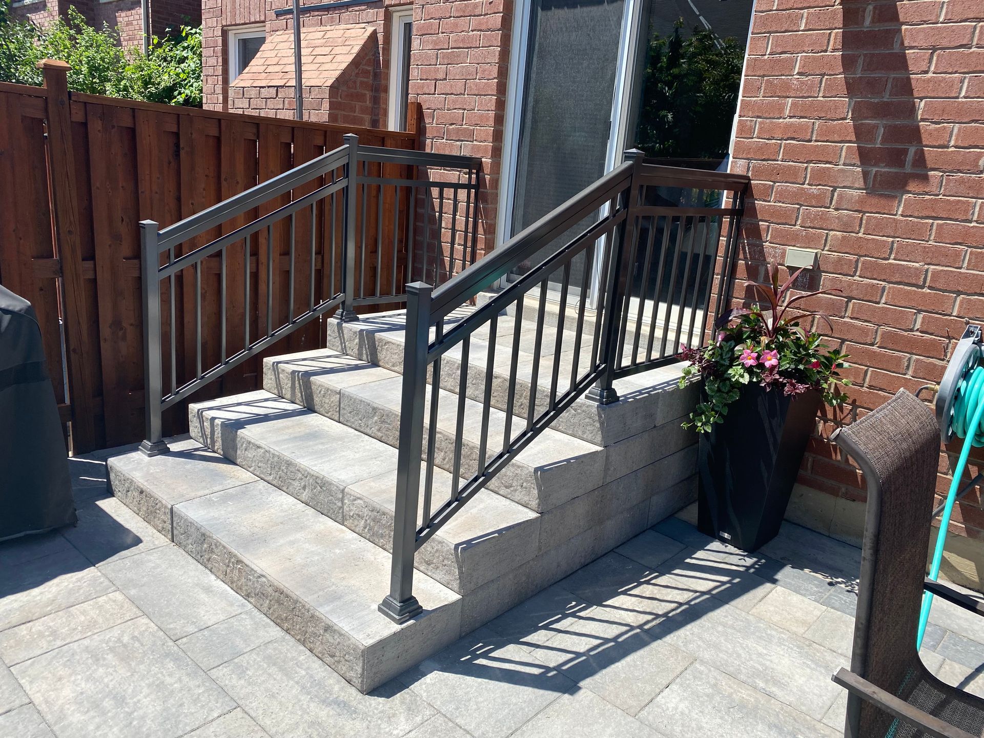 Stone steps with metal handrails leading to a door, next to a brick wall.