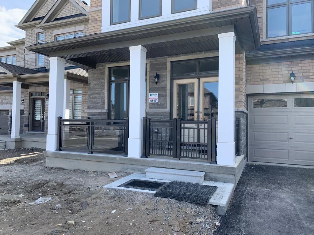 A house with a porch and a garage under construction.
