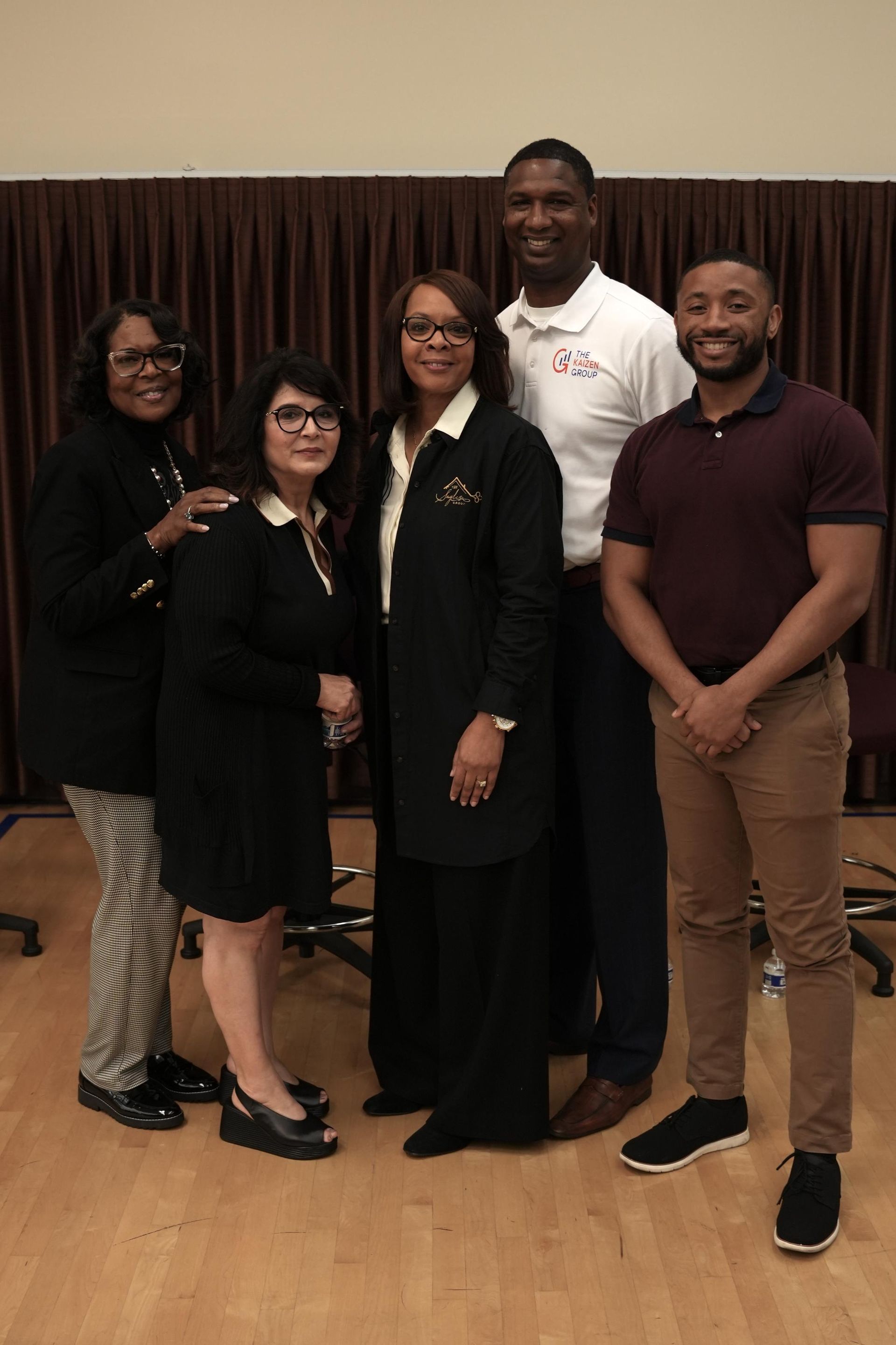 A group of people standing next to each other on a wooden floor.