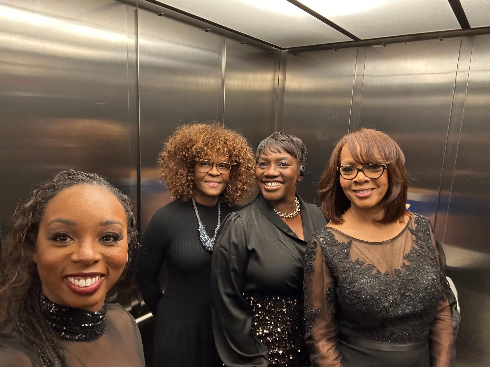 Four women are posing for a picture in an elevator