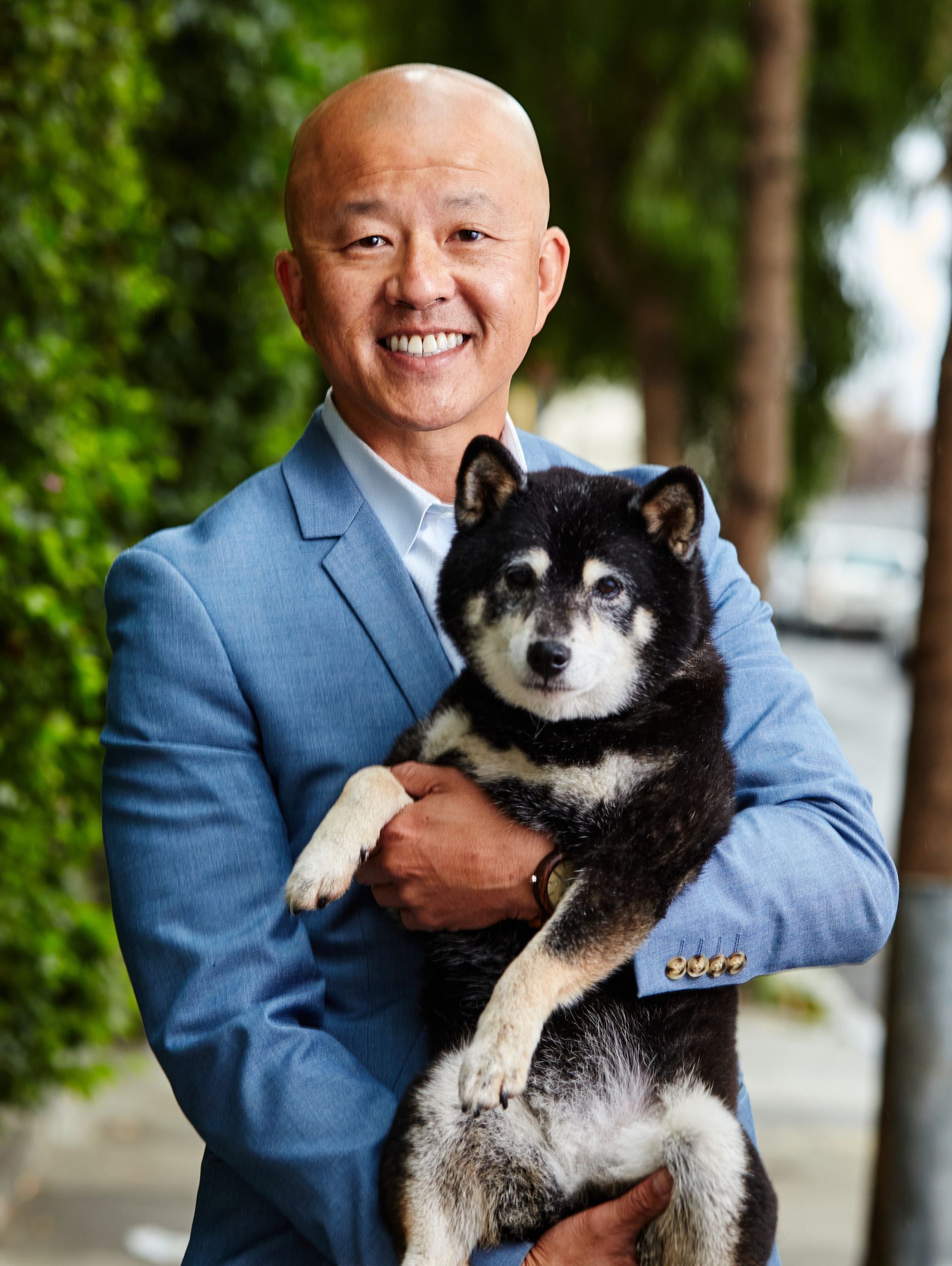 A man in a suit is holding a black and white dog.