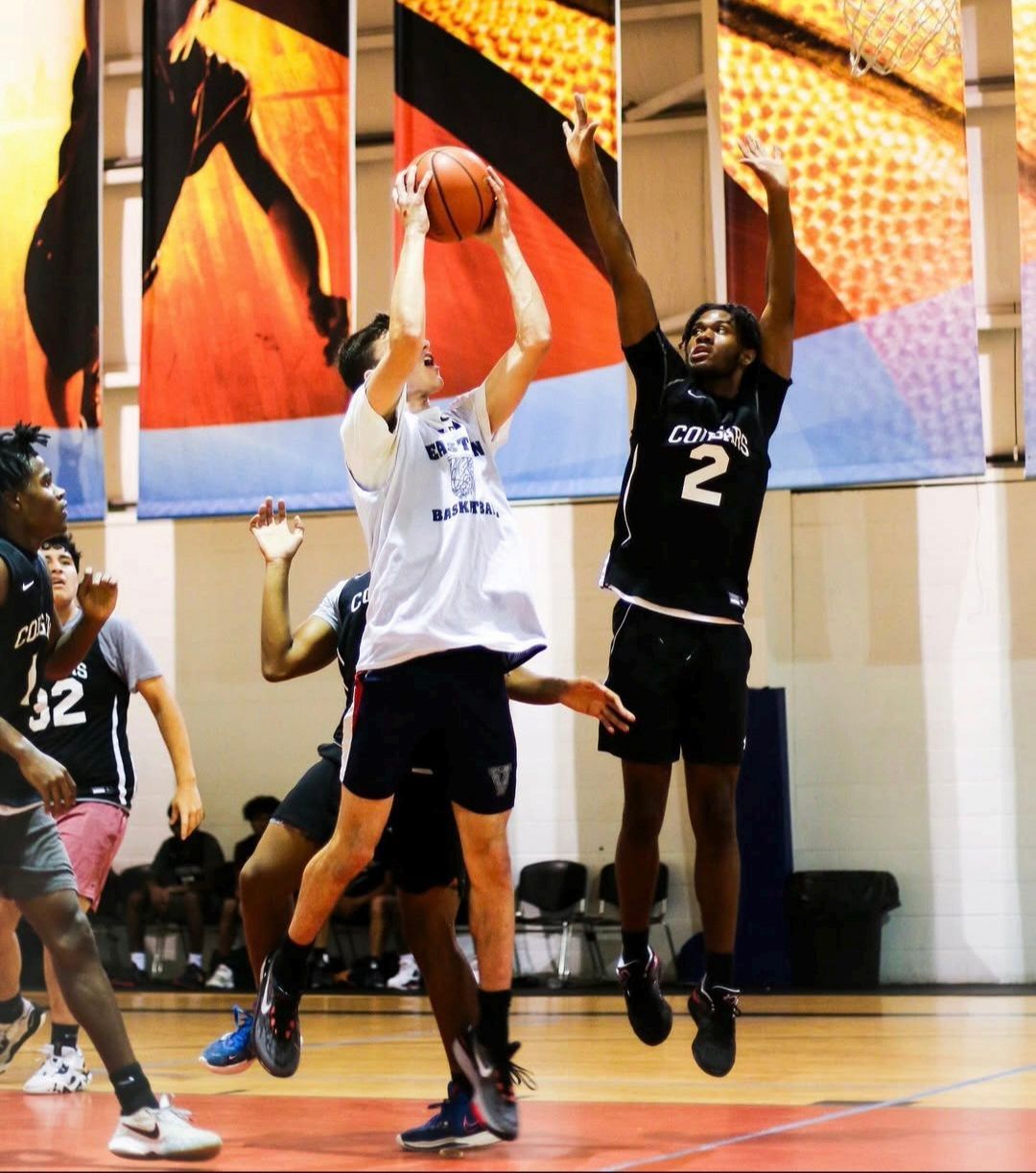 Two smiling boys with arms around each other in a park. One wears a track shirt, the other a striped shirt.