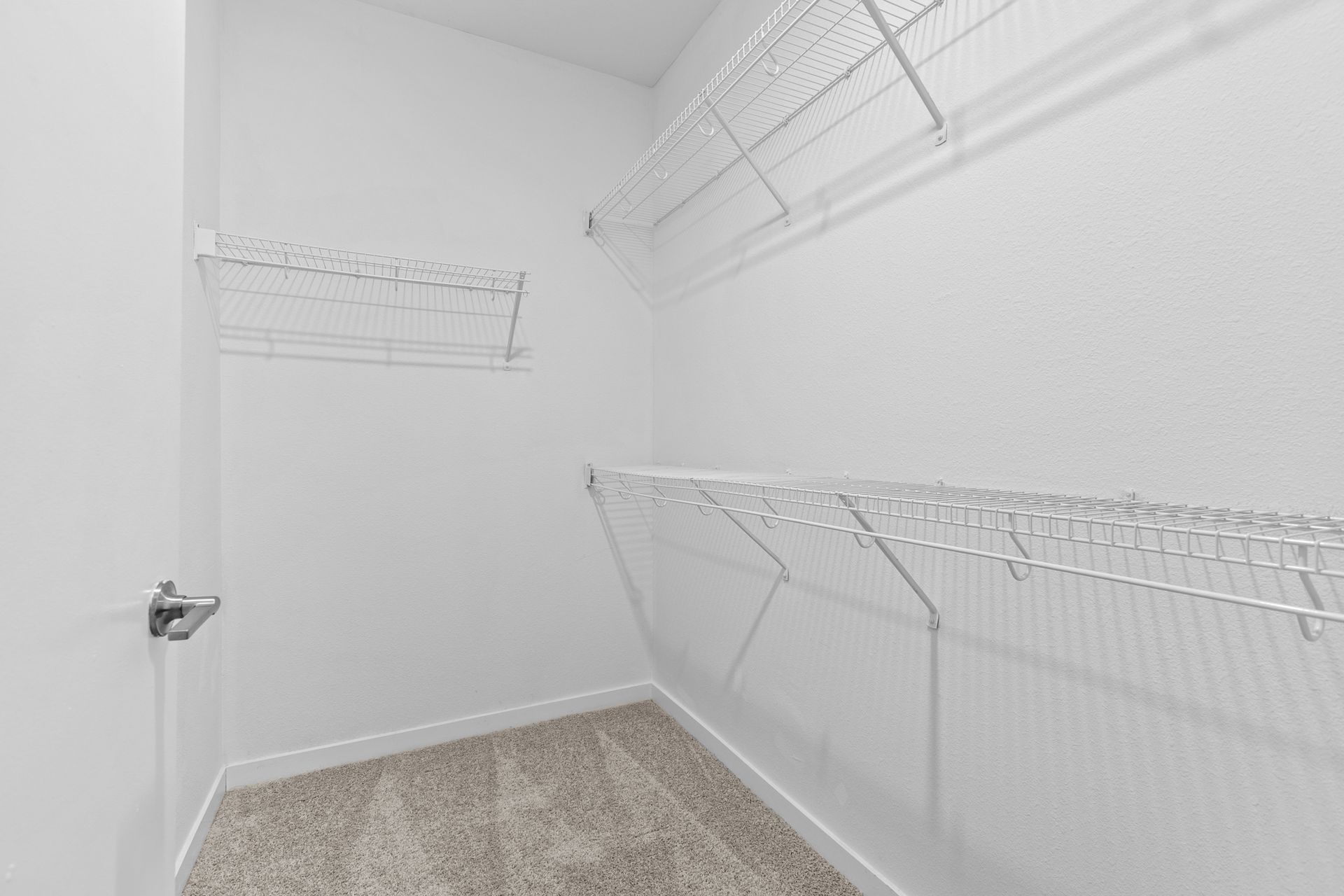A walk in closet with lots of shelves and a door.