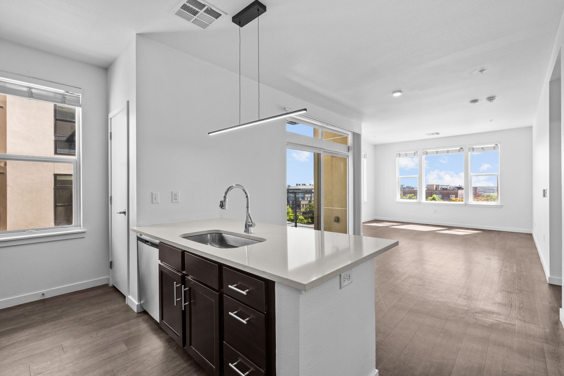 An empty apartment with a kitchen , living room , and dining room.