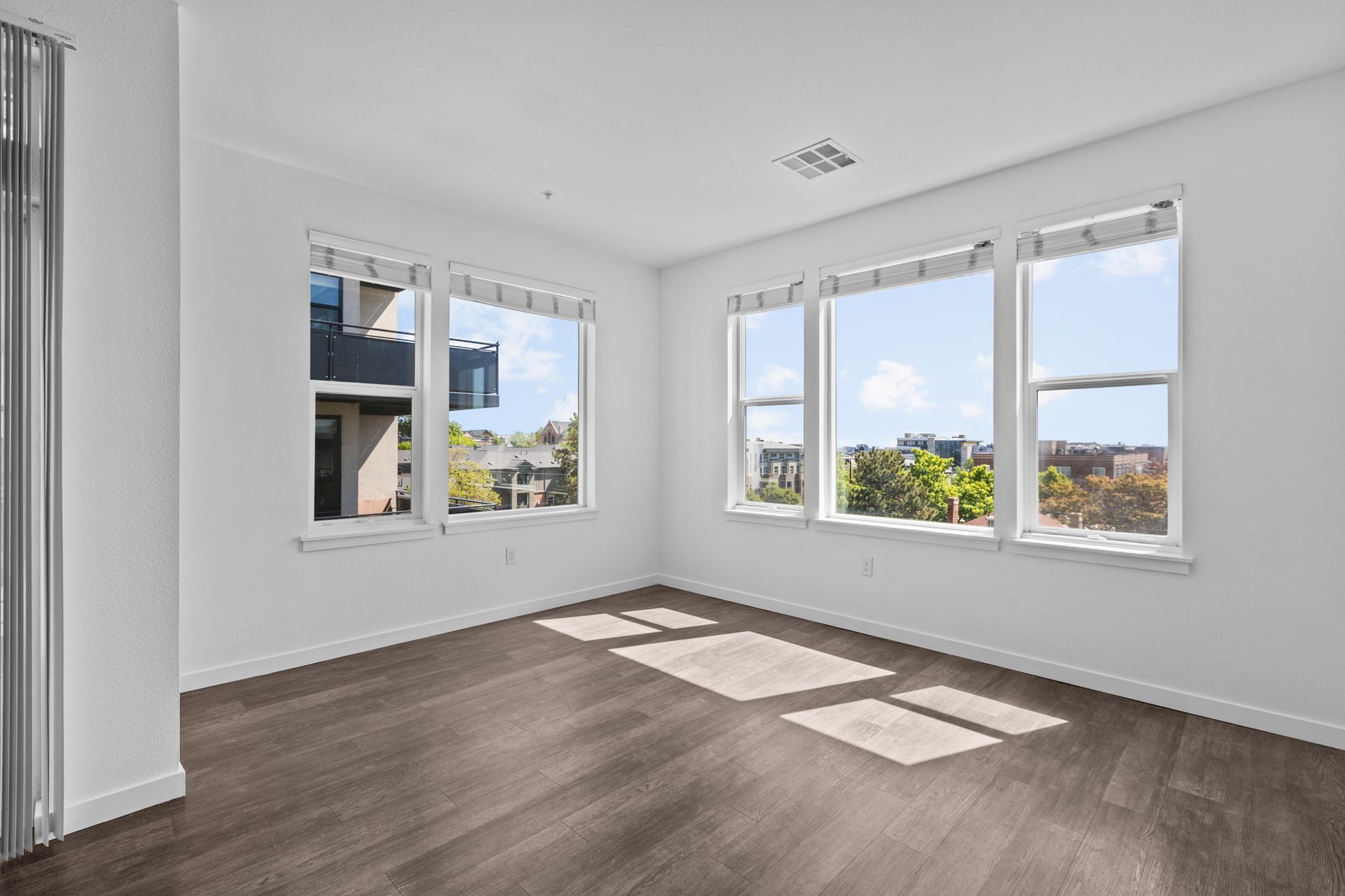 An empty living room with hardwood floors and lots of windows.