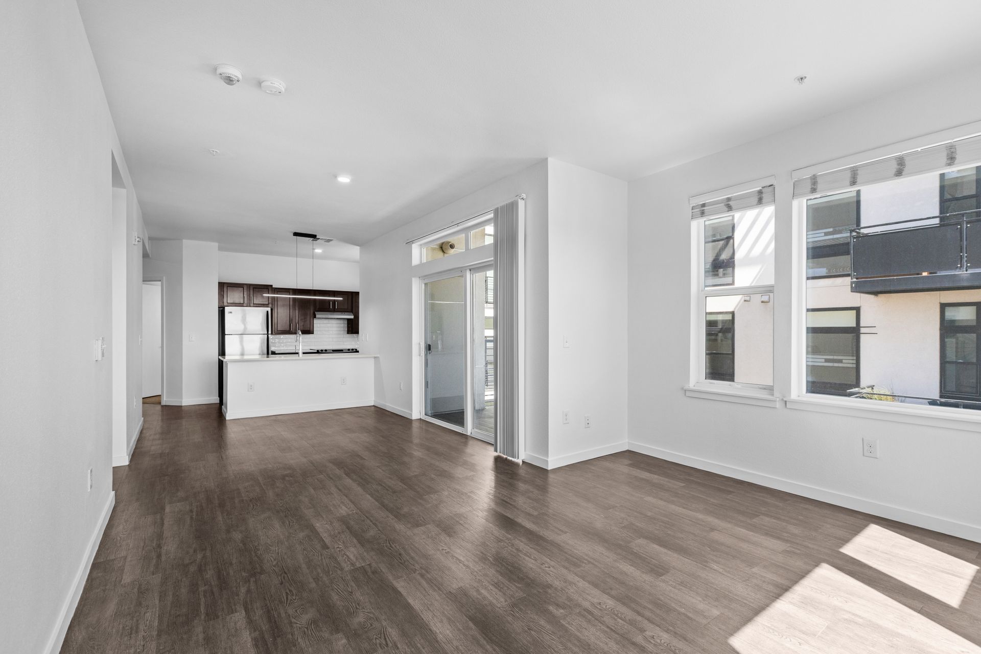 An empty living room with hardwood floors and white walls.