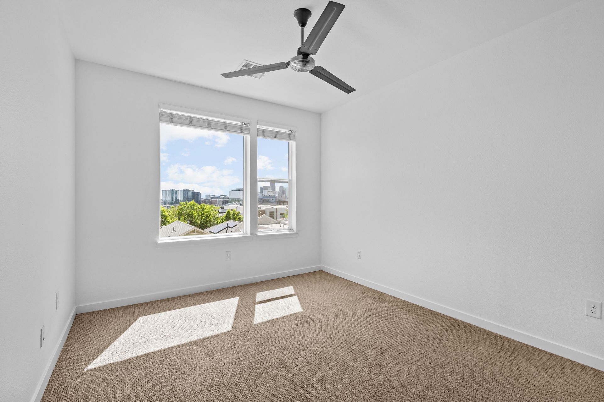 An empty bedroom with a ceiling fan and a window.