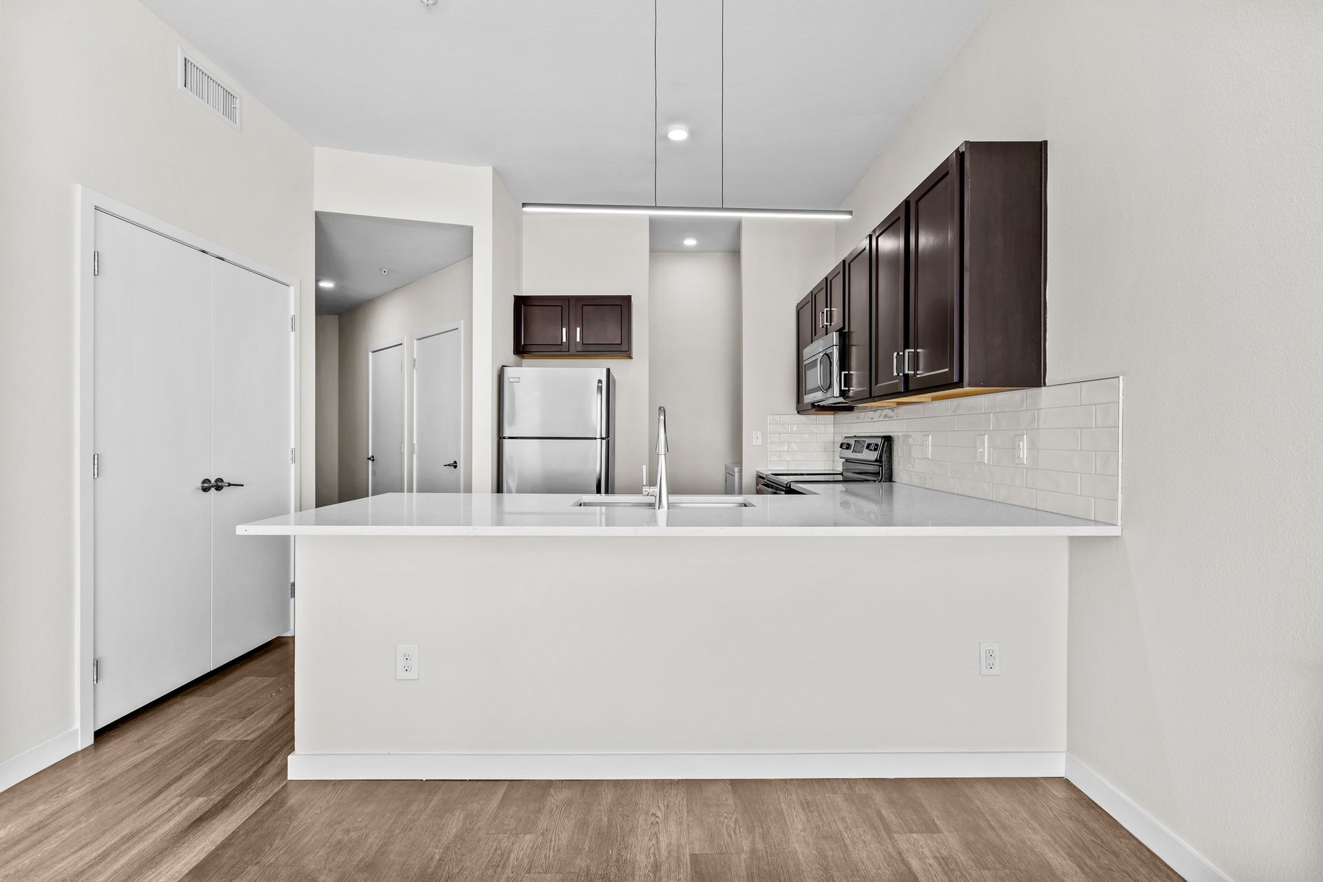 A kitchen with a refrigerator , sink , microwave , and cabinets.