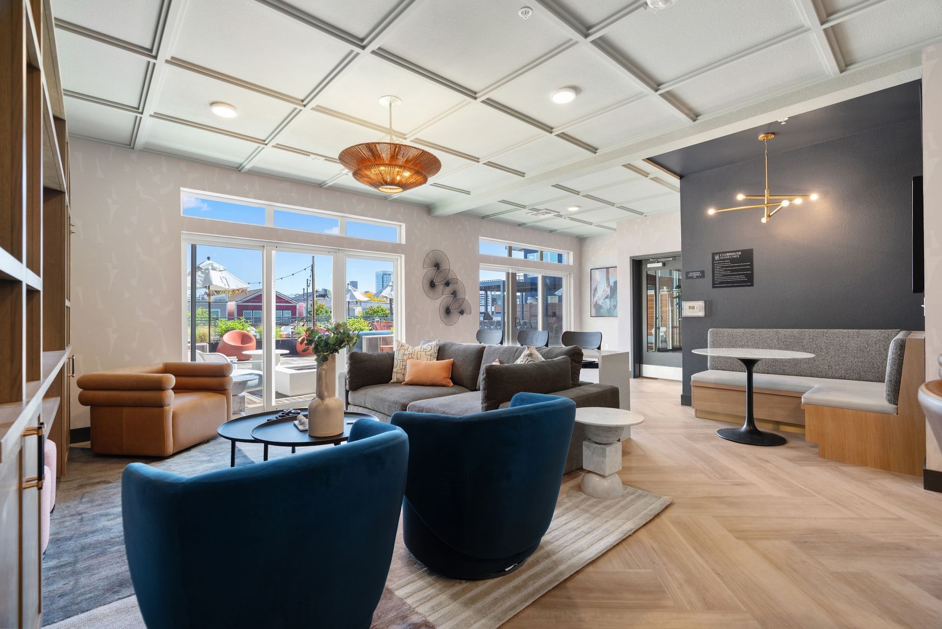 Cozy lounge with blue armchairs, couches, and marble tables; near large windows, a door, and an ornate ceiling.