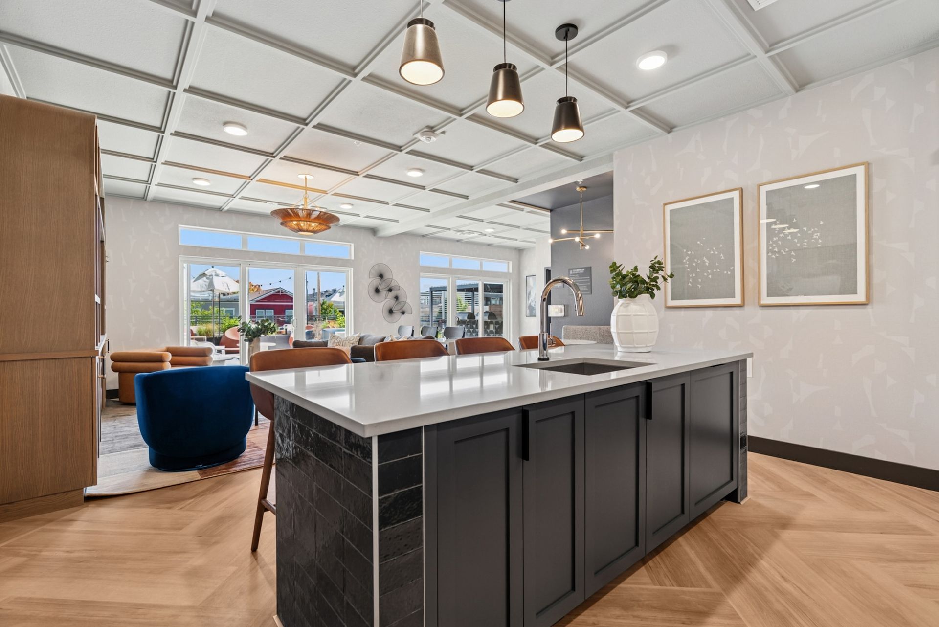 Modern kitchen with a large island, pendant lights, and windows.