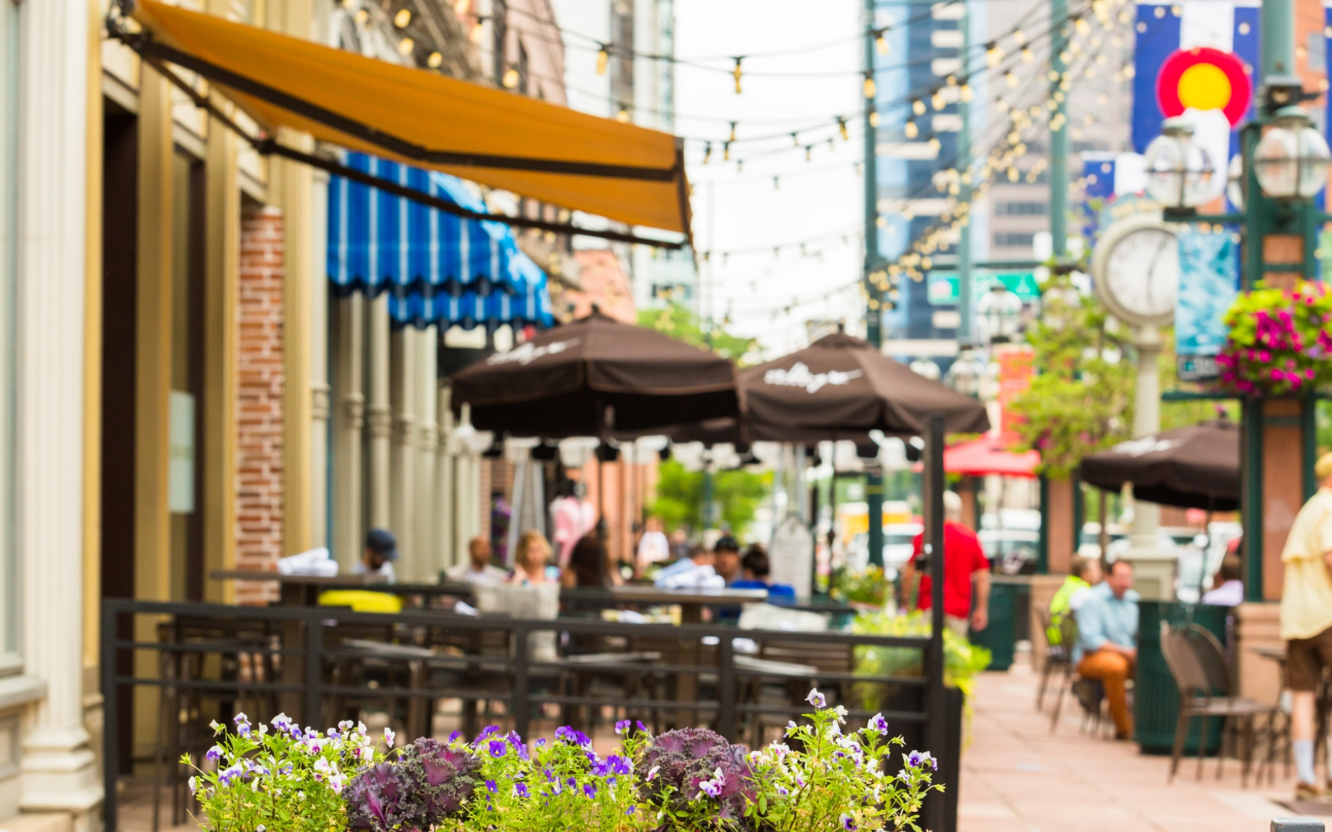 A group of people are sitting at tables outside of a restaurant.