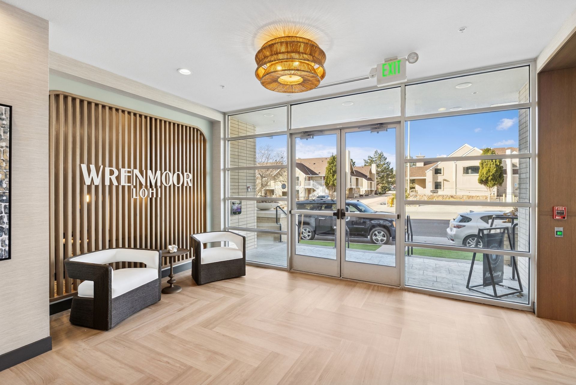 Lobby with seating, large windows, and door to the outside. Wooden accents and modern light fixture.