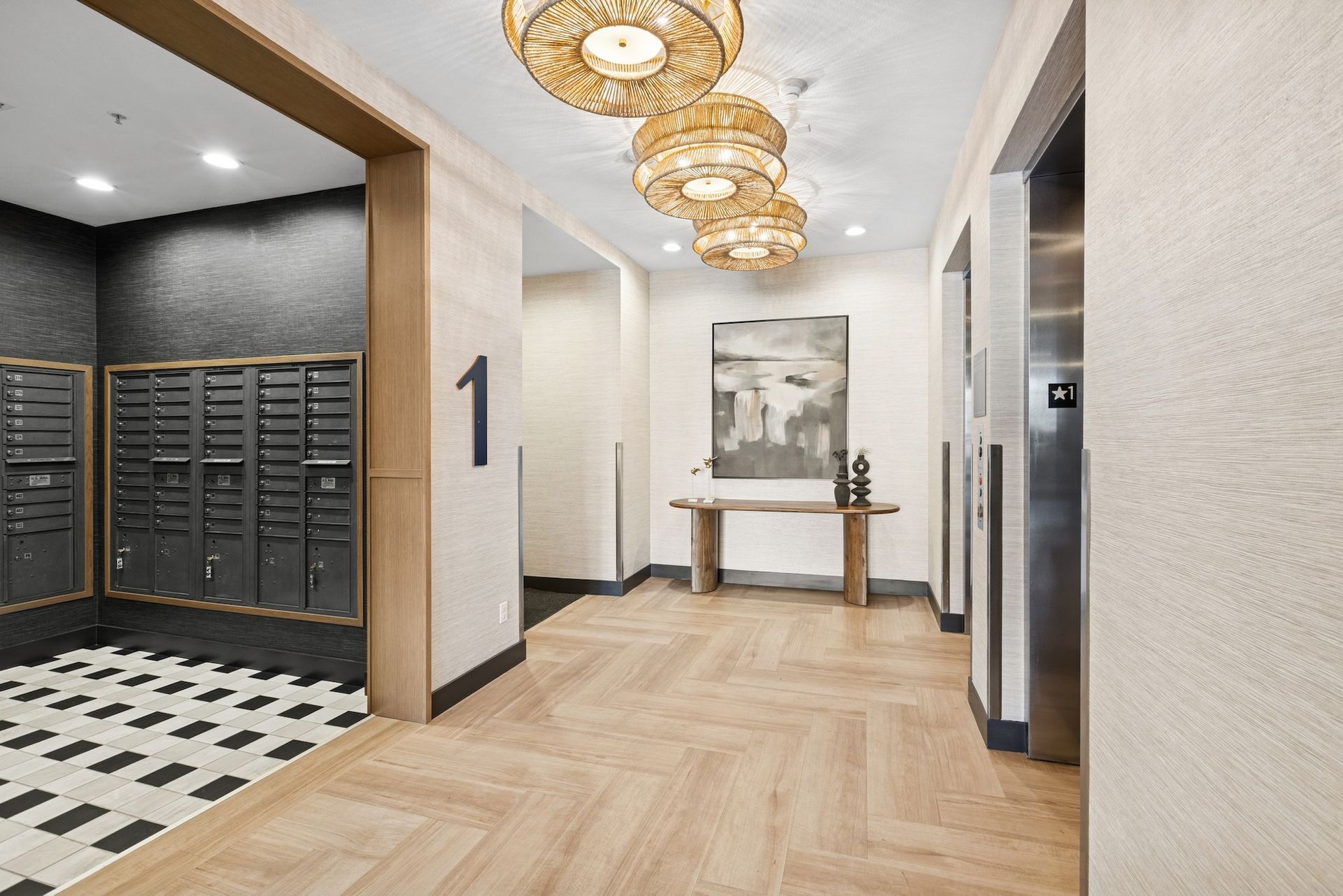 Hallway with herringbone wood floor, mailboxes, elevator, artwork, and decorative ceiling lights.