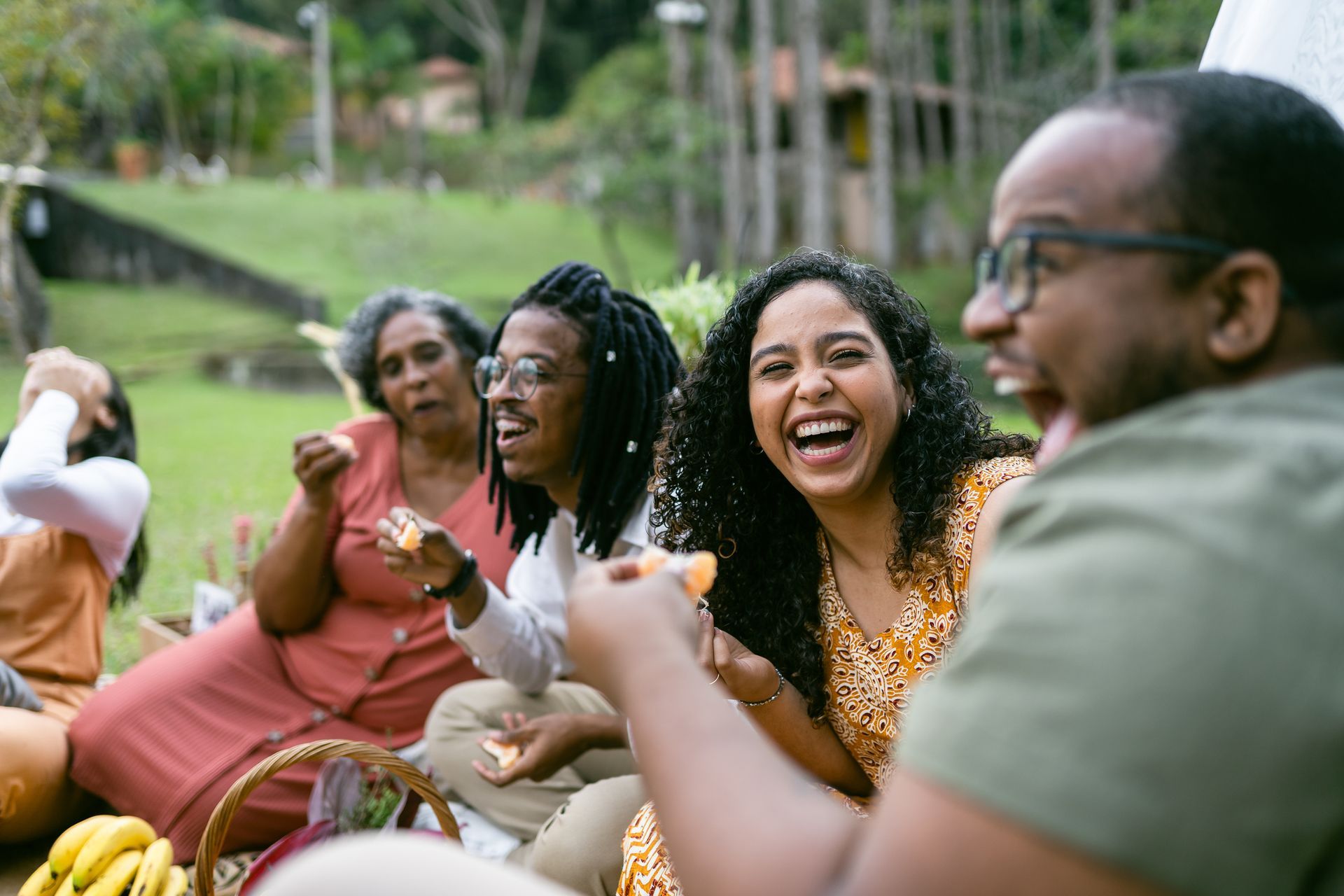 Smiling friends enjoying a picnic together at a scenic holiday park during a sunny afternoon outing