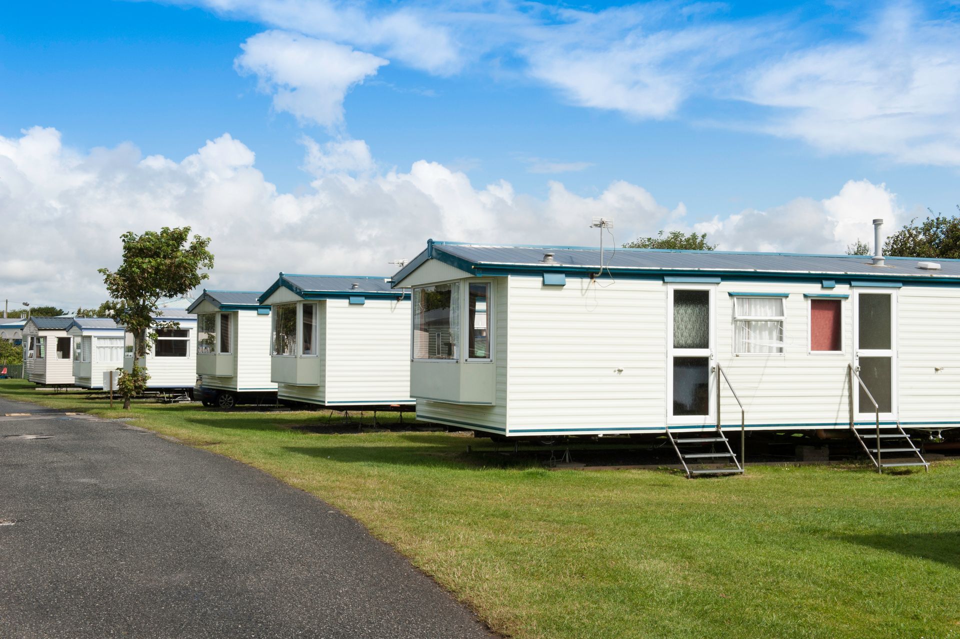 Caravans lined up at a scenic caravan park with greenery and open skies around