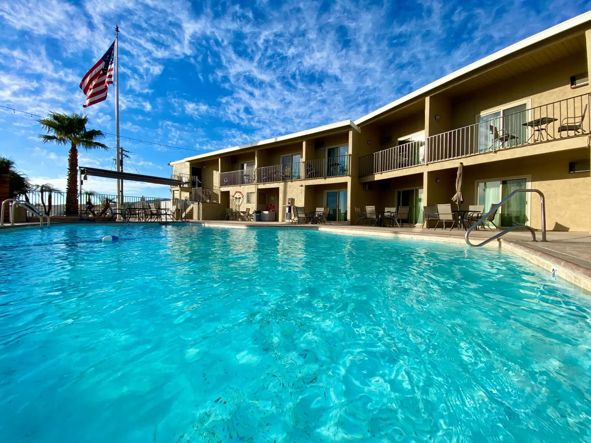 There is a large swimming pool in front of a hotel.