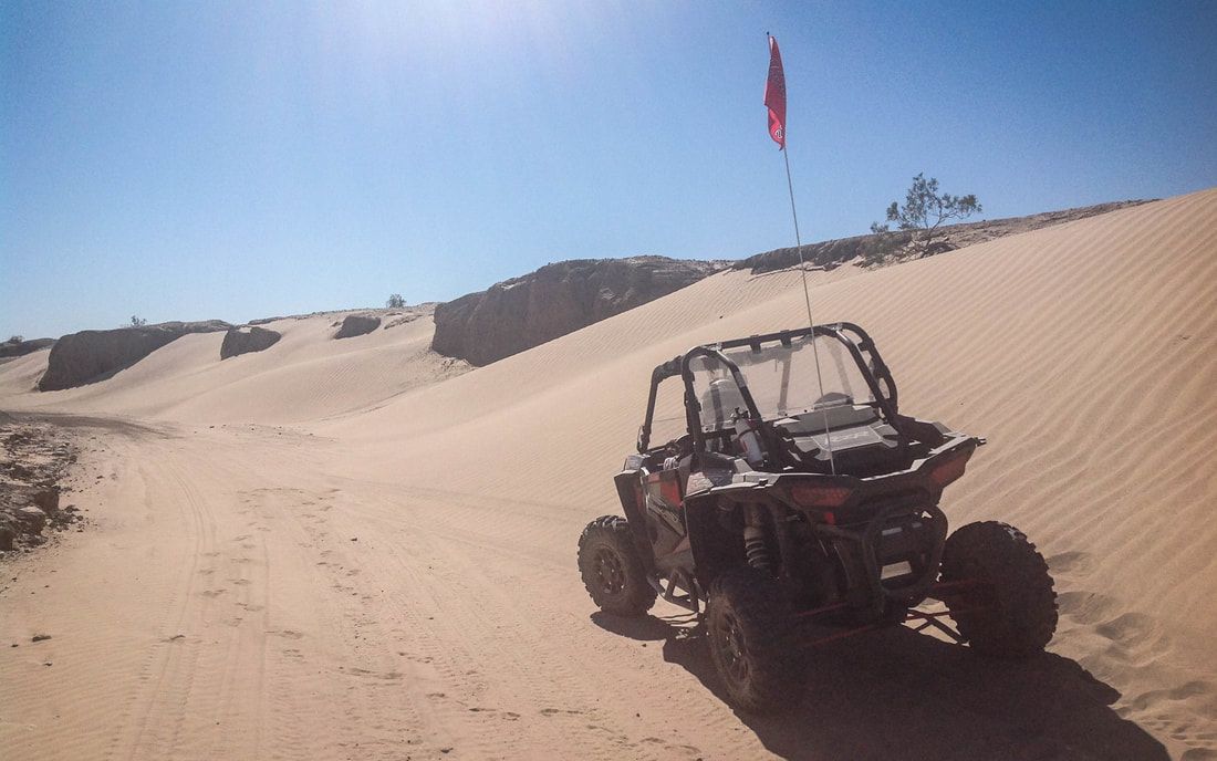 A atv is driving down a sandy road in the desert.