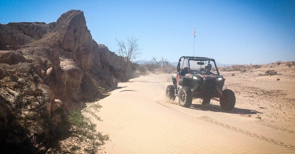 A person is driving a atv on a dirt road in the desert.