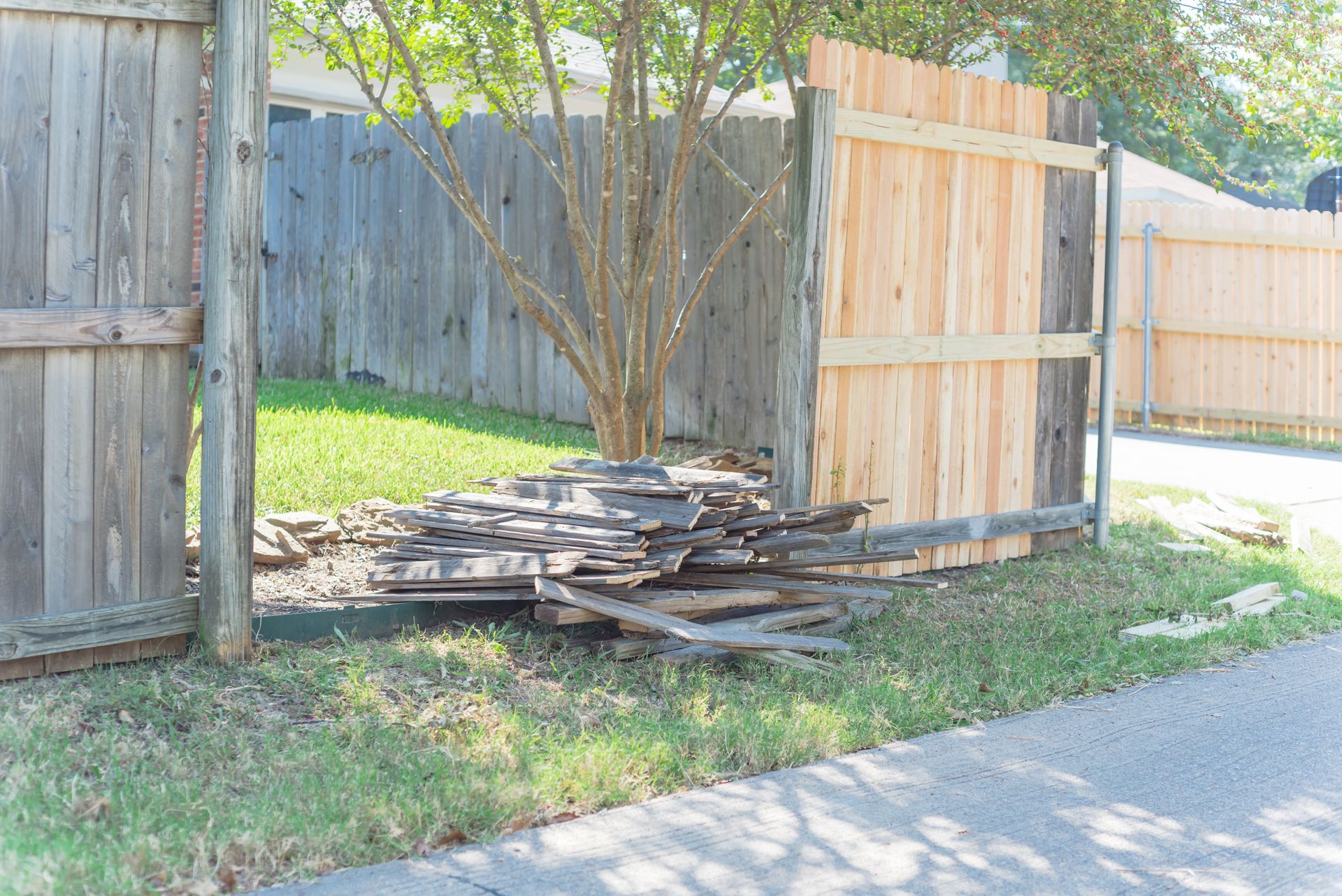 Aged wooden fence near new lumber boards.