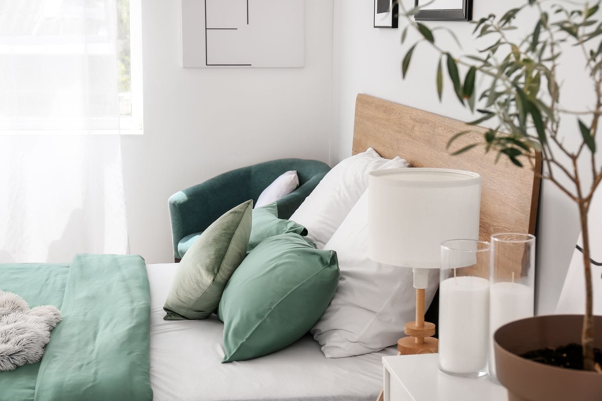 Bedroom with a wooden bed, nightstand, and two windows with view of lush greenery.