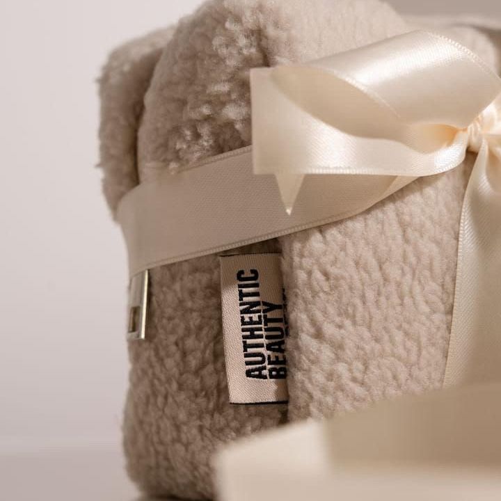 Eine Nahaufnahme einer Decke mit einer weißen Schleife und einem Etikett mit der Aufschrift „Authentische Schönheit“.