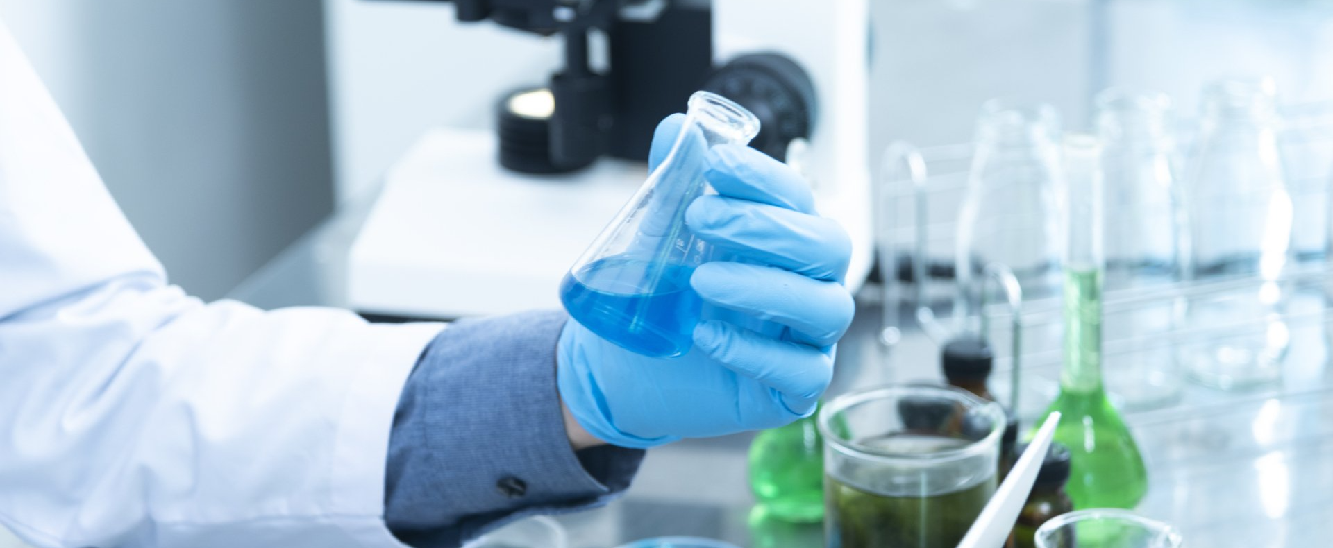 A scientist is pouring liquid into a beaker in a laboratory.