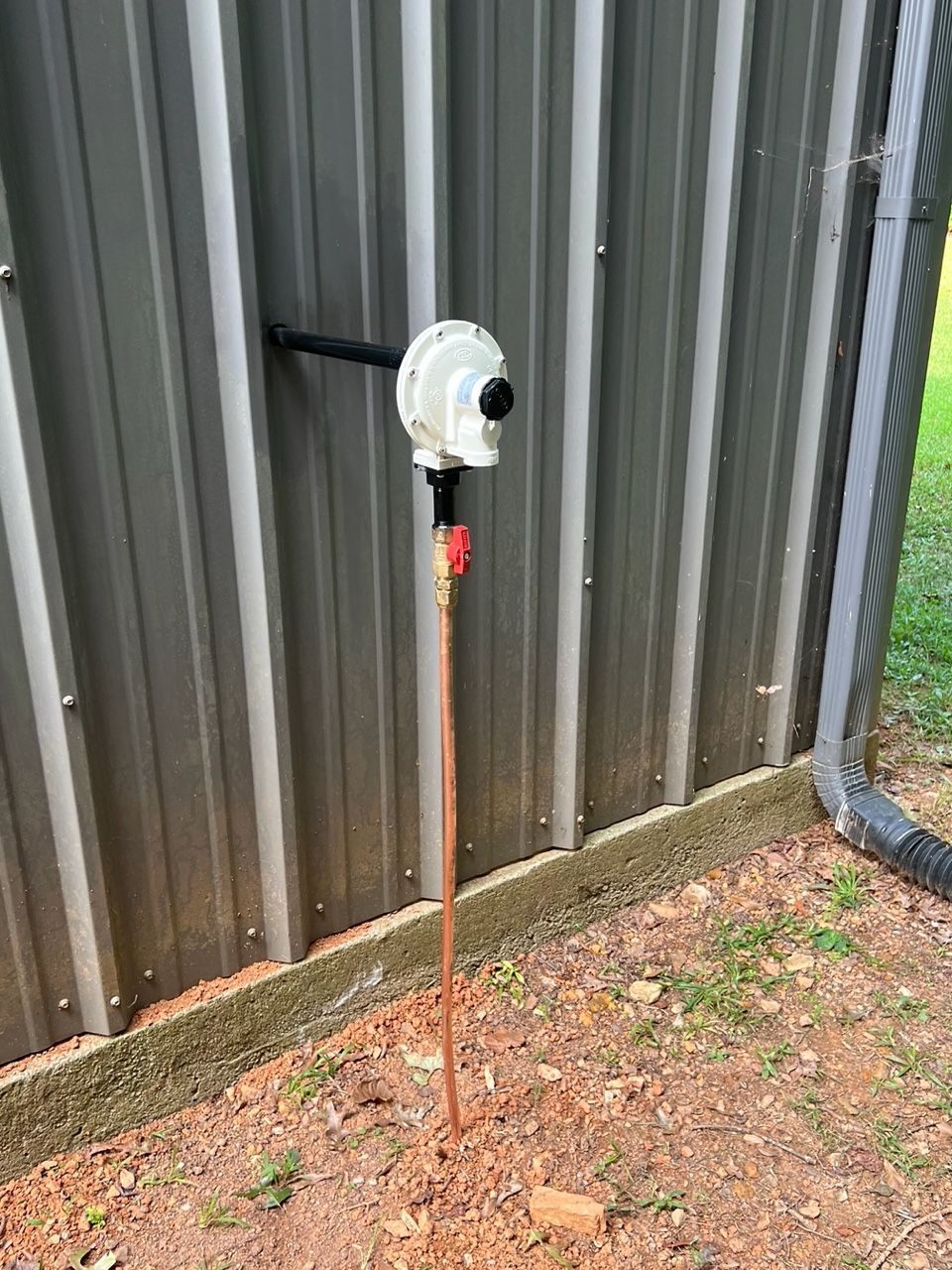 Woman in straw hat smiles, holding wine glass near a lake.