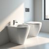 Un bidet e un water bianchi in un bagno minimalista con rubinetto cromato e pulsante di scarico.