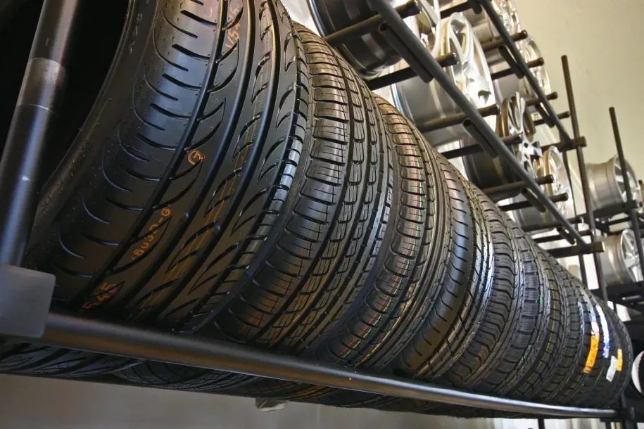 A row of new black car tires arranged on a metal rack in a tire shop.
