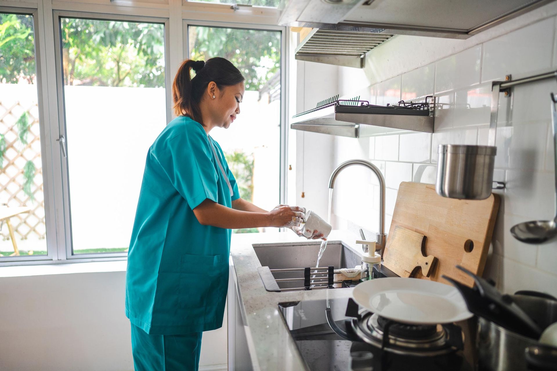 Nurse in medical scrubs washing the dishes — Birmingham, AL — Helping Hand Services Inc