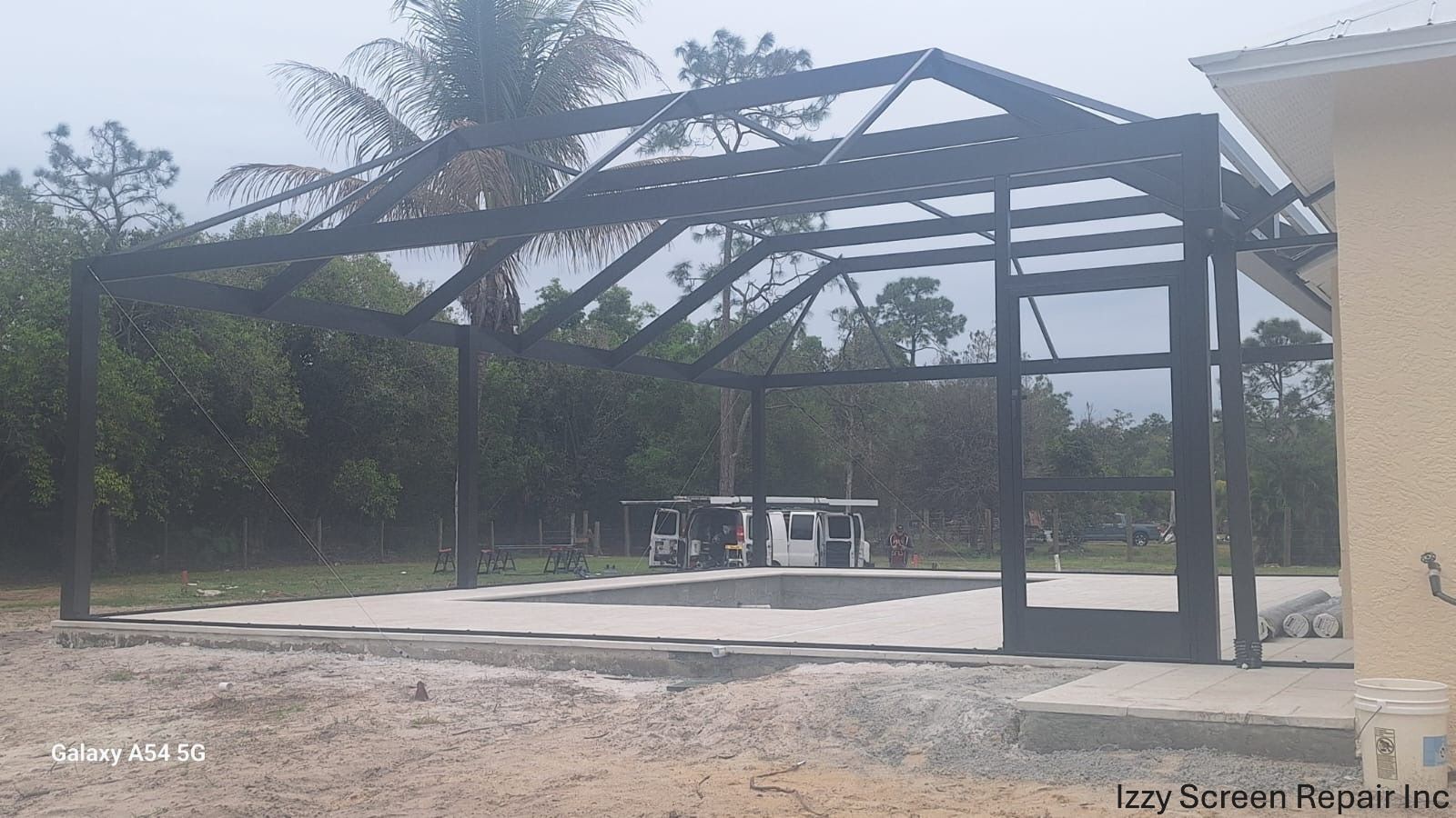 A screened in porch is being built in the backyard of a house.