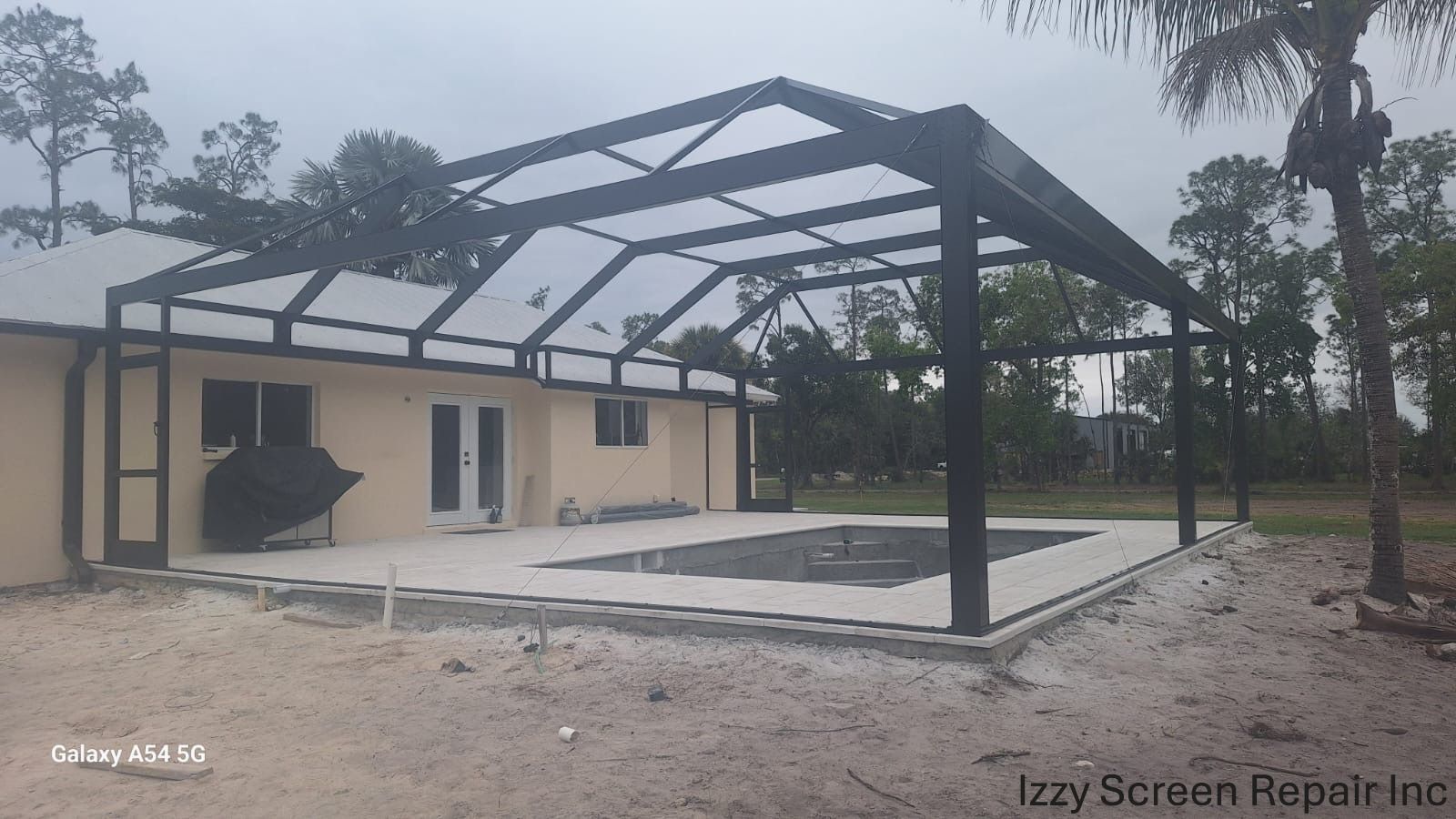 A picture of a house with a screened in swimming pool.