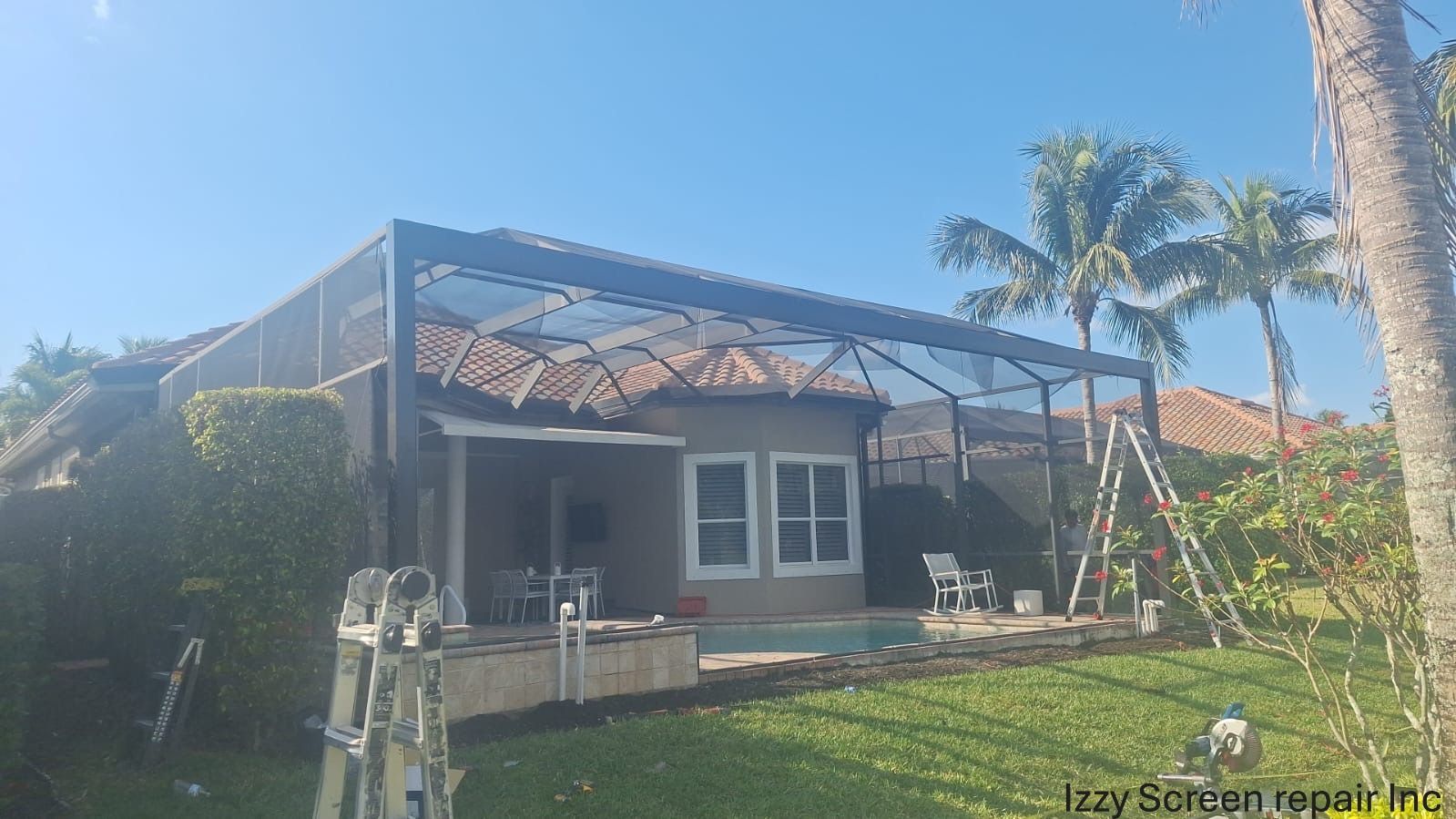 A house with a screened in porch and a ladder in front of it.