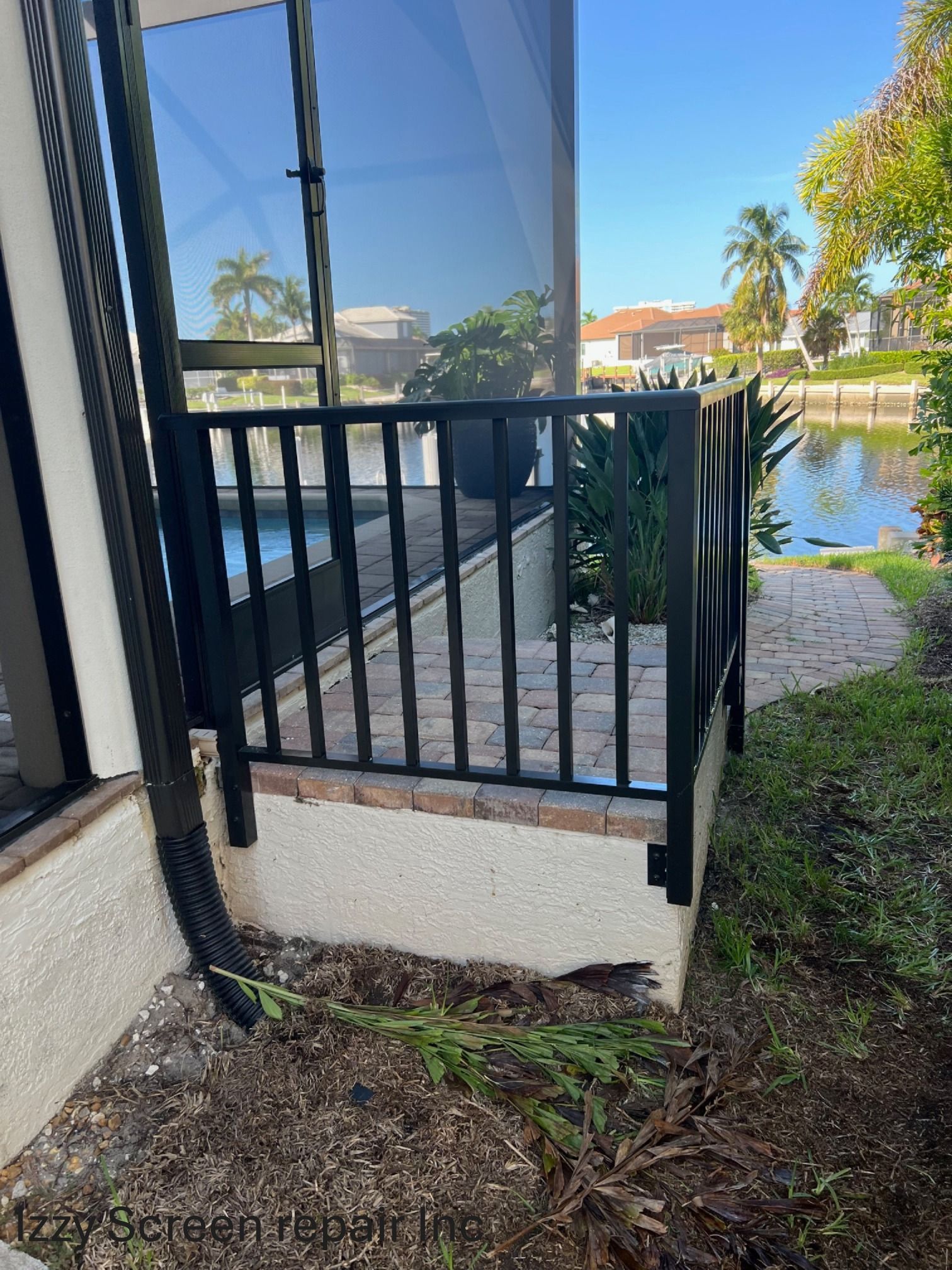 A black railing is sitting next to a screened in porch.